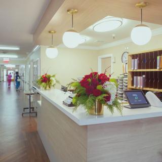 A spacious reception area featuring a desk adorned with red floral arrangements and modern lighting.