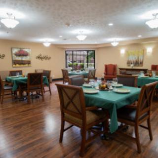 A spacious dining area featuring tables with green tablecloths, surrounded by comfortable chairs and ambient lighting.
