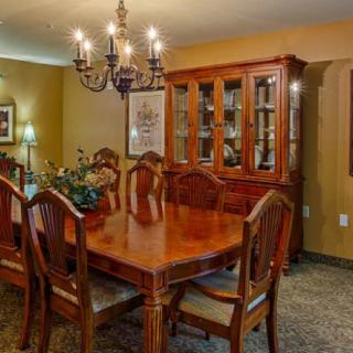 A cozy dining room featuring a wooden table and chairs, illuminated by a chandelier.