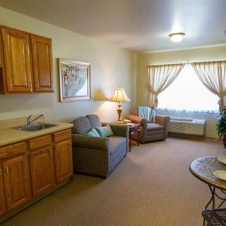 A cozy living room with comfortable seating, natural light, and wooden cabinetry.