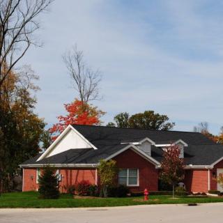 A brick house in a suburban neighborhood with autumn trees.