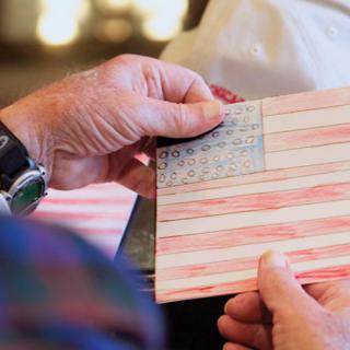 A person holding a handmade drawing of the American flag.