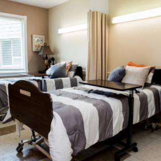 A hospital room with two neatly arranged twin beds separated by a curtain.