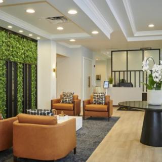A modern lobby with comfortable seating, a green wall, and a welcoming reception desk.