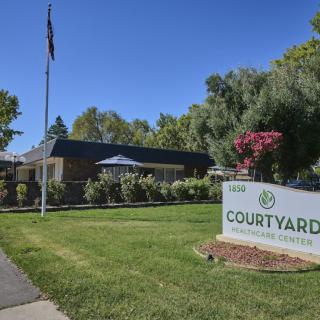 A building with a courtyard sign, surrounded by trees and a well-maintained lawn.