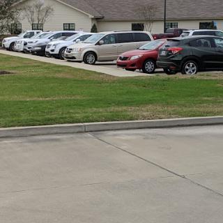 A view of a parking lot filled with various cars in front of a building.