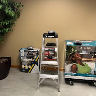 An interior office setting featuring a ladder, promotional displays, and a decorative plant.