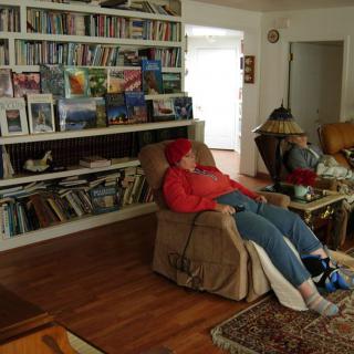 Two people relaxing in recliner chairs in a cozy living room with bookshelves.