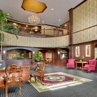A spacious hotel lobby with classic interior design, featuring elegant furniture and a grand chandelier.