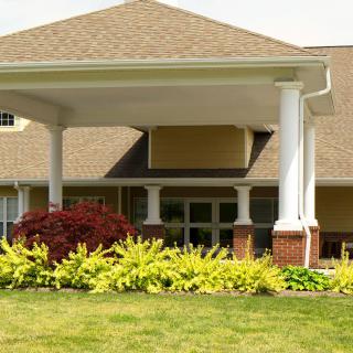 A well-landscaped building entrance with columns and a peaked roof.