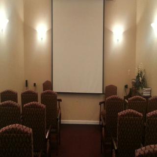 A small conference room with arranged chairs facing a projector screen.