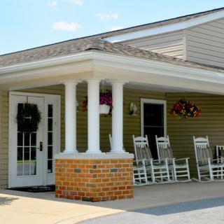 A cozy porch with rocking chairs and flowers at the entrance of a building.