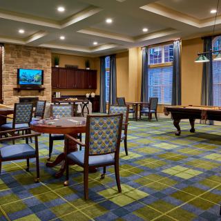 A spacious game room featuring a pool table, various seating areas, and a television.