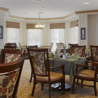 An elegant dining room with ornate chairs and tables set near large windows.