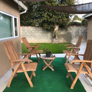 A cozy backyard patio with wooden chairs and a small table on a green carpet.