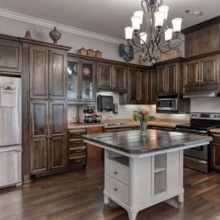 A modern kitchen with wooden cabinets, a central island, and a chandelier.