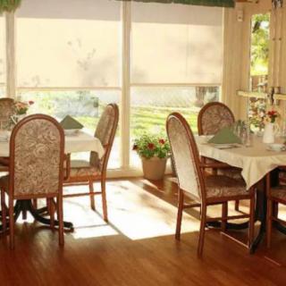 A cozy restaurant interior with sunlight streaming through large windows, illuminating the dining tables and chairs.