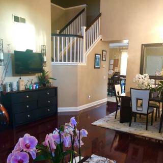 A spacious living and dining area with a staircase, featuring elegant furniture and vibrant decor.