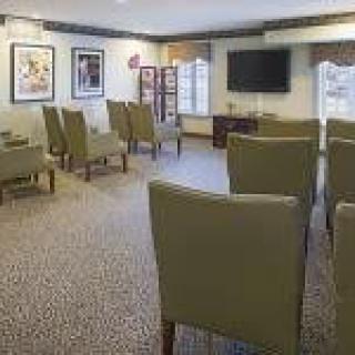A small meeting room with rows of chairs facing a television, decorated with artwork on the walls.