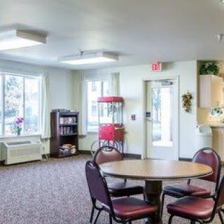 A cozy common area with a round table, chairs, and a popcorn machine.