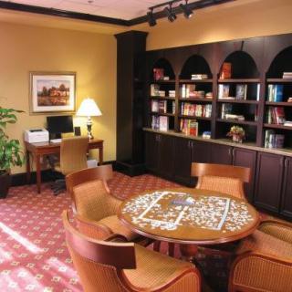A cozy library space with a puzzle on the table, surrounded by bookshelves and comfortable chairs.