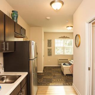A cozy apartment showcasing a modern kitchen leading into a compact living room with ample natural light.