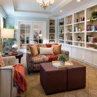 A cozy and elegant living room featuring a comfortable sofa, an armchair, and a well-organized bookshelf.