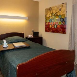 A cozy hotel room with a single bed and colorful artwork on the wall.