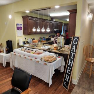 A buffet setup in a kitchen with a variety of dishes and a 'GATHER' sign, indicating an event or gathering.