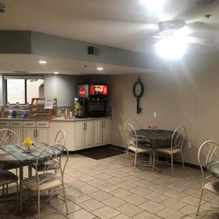 A cozy dining area with tables and chairs, featuring a beverage station in the corner.