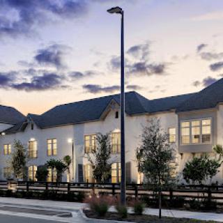 A modern residential building illuminated during the evening, showcasing contemporary architecture under a scenic sky.