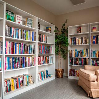A cozy reading corner in a library with bookshelves and an armchair.