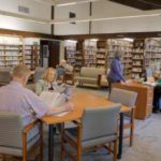 People reading and browsing in a library filled with books.