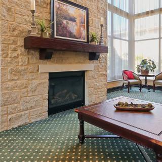 A cozy living room with a stone fireplace and large windows.