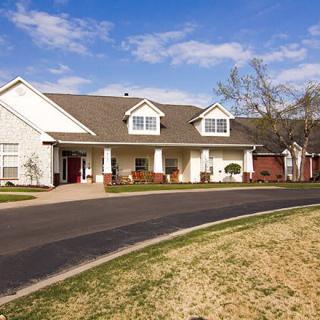 A residential house with a spacious driveway under a clear blue sky.