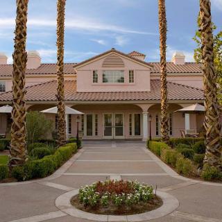 A large house with a pathway lined by palm trees and well-maintained landscaping.
