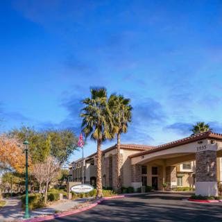 A hotel entrance with palm trees under a clear, sunny sky.