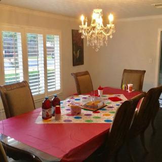 A dining room with a chandelier, featuring a table set with a colorful cloth and chairs around it.