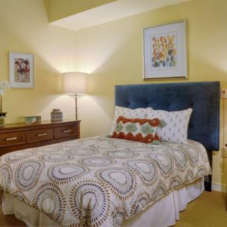 A cozy bedroom with a decorative bedspread and elegant artwork.