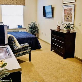 A cozy bedroom with a bed, dresser, and wall-mounted television.