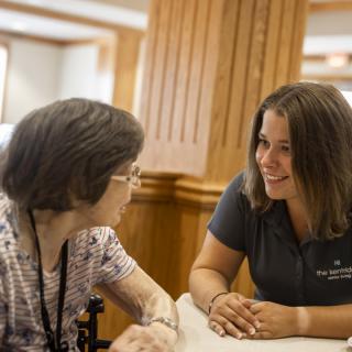 A caregiver having a conversation with an elderly woman in an indoor setting.