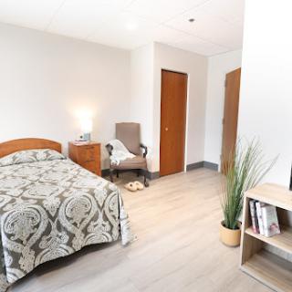 A cozy and well-lit bedroom featuring a comfortable bed, relaxing chair, and decorative elements.