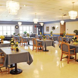 A spacious dining area with neatly arranged tables and chairs, adorned with elegant chandeliers.