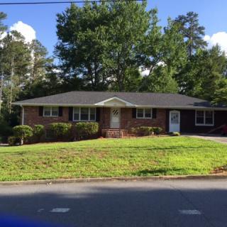 A single-story brick house with a well-maintained lawn and surrounding trees.