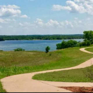 A winding pathway leading to a scenic lake under a partly cloudy sky.