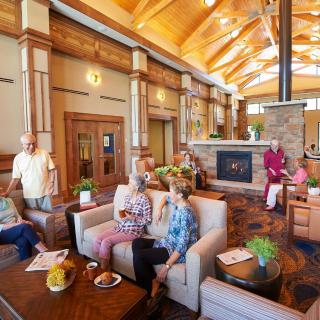 A cozy lounge area with seniors socializing near a fireplace.