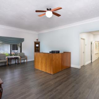 A bright and spacious reception area featuring a wooden front desk, comfortable seating, and modern decor.