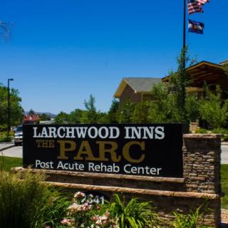 A sign for Larchwood Inns Post Acute Rehab Center surrounded by landscaping and flags.
