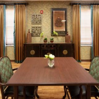 A traditional dining room with a wooden table, chairs, and decorative elements.
