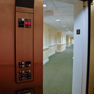The image shows an open elevator door revealing a carpeted hallway on the third floor.